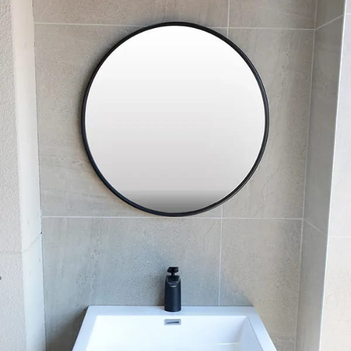 Round custom wall mirror with slim black frame installed above bathroom basin